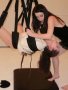 Long-haired brunette jeering her suspended on a sling friend